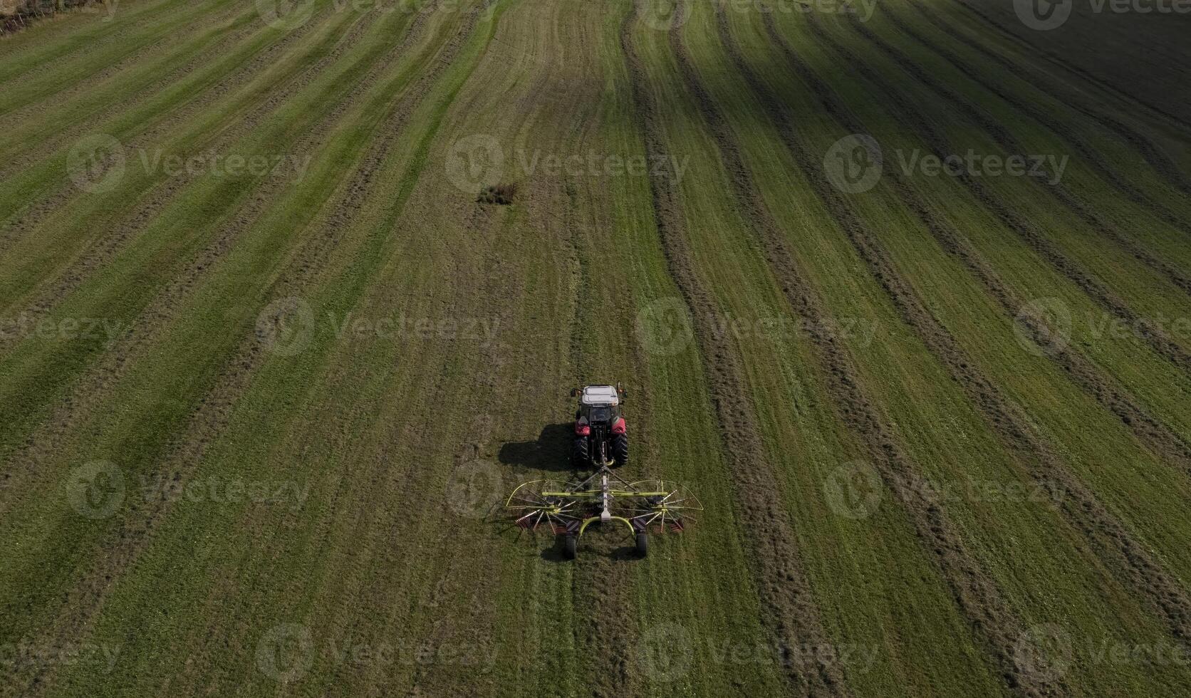 Aerial View of Tractor Tedding Hay in a Green Field photo