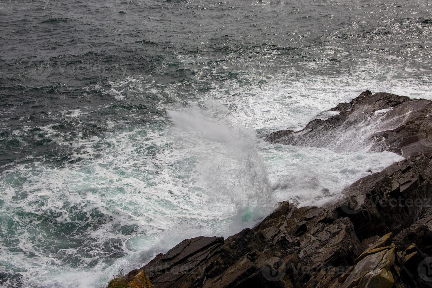 Powerful Waves Crashing Against Rugged Coastline, in Ireland photo