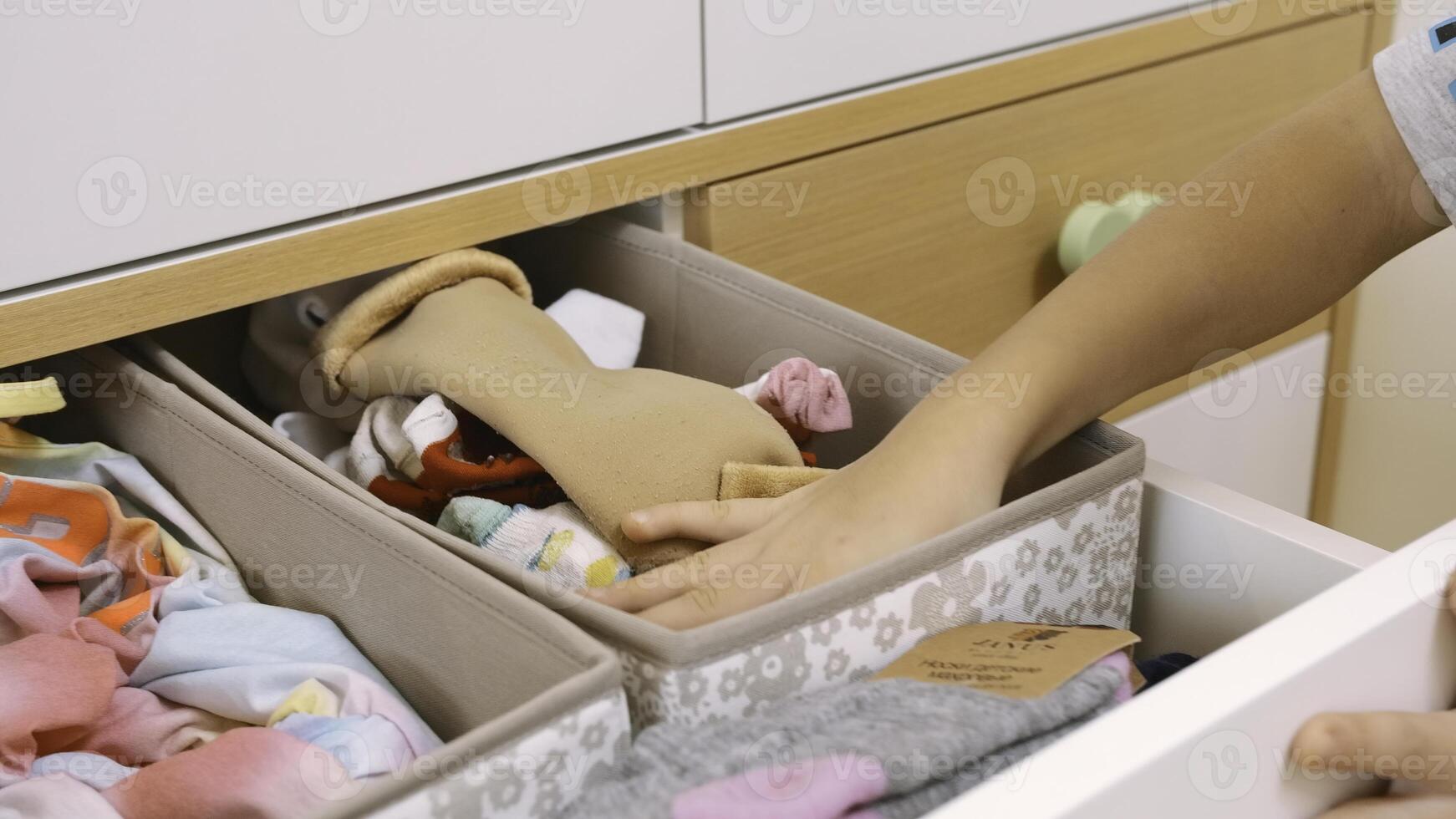 Woman's hand opens drawer with neatly folded socks. Creative. Selecting brown socks and closing the drawer. photo