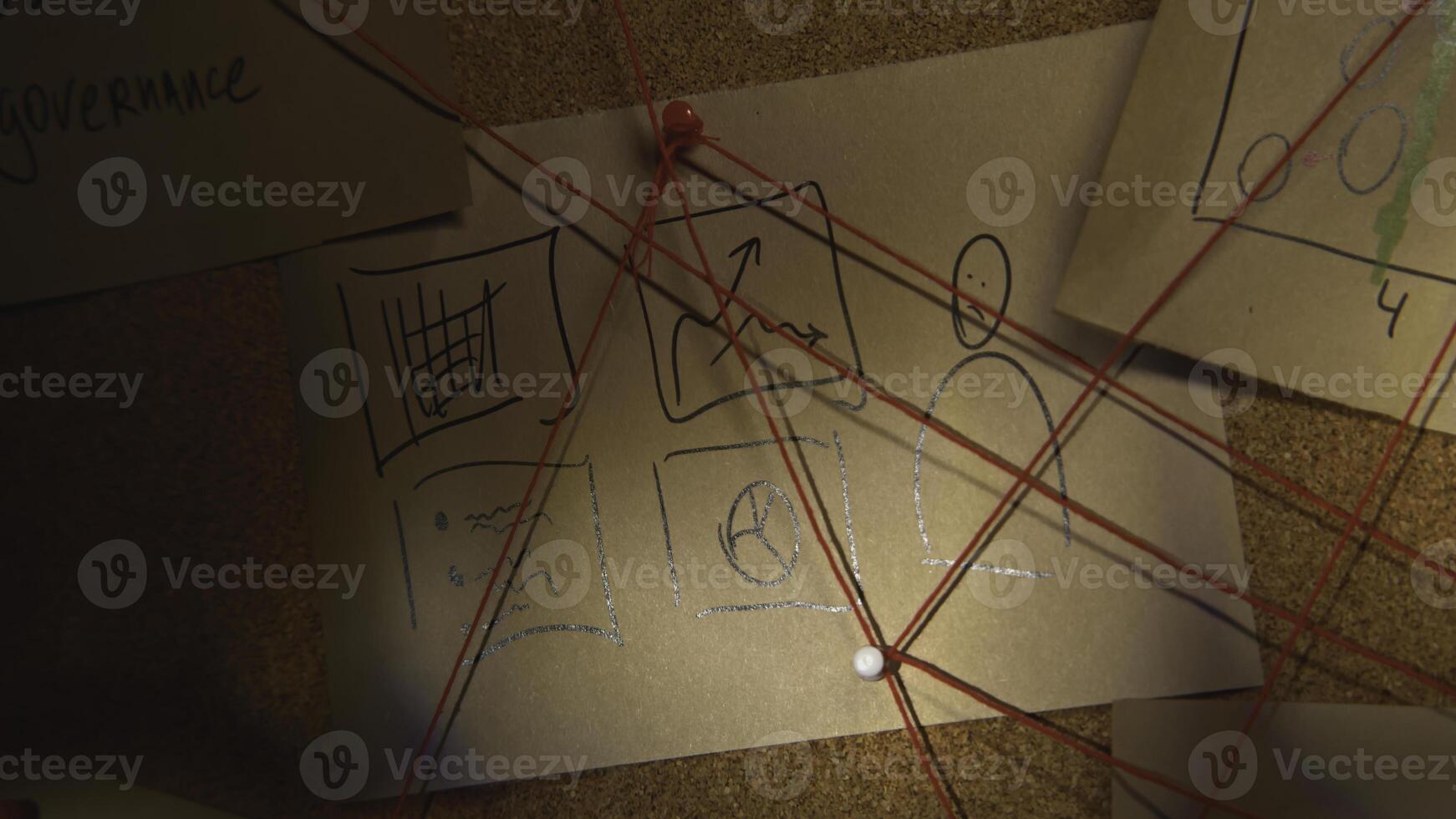 Close-up lighting of notes on board. Stock footage. Flashlight illuminates secret notes on board with threads. Red threads intersect on board with mysterious notes photo