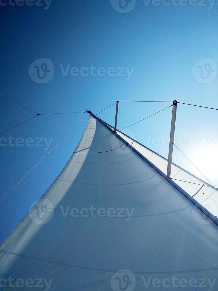 View of the bright sun over the yacht's sail on a clear summer day photo