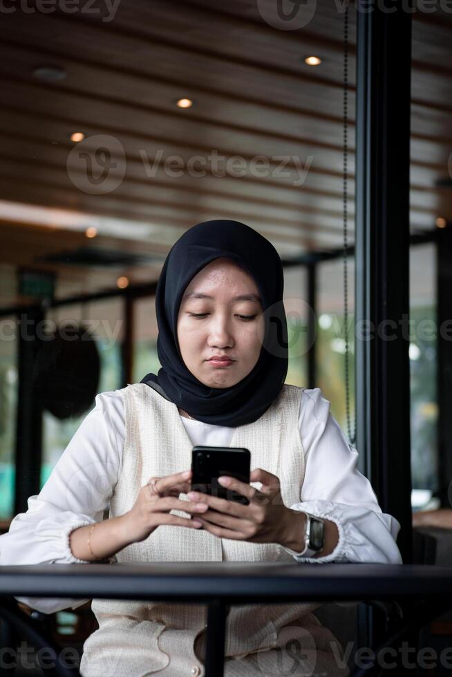 portrait of beautiful Asian woman in hijab. receive a message with a sad facial expression photo