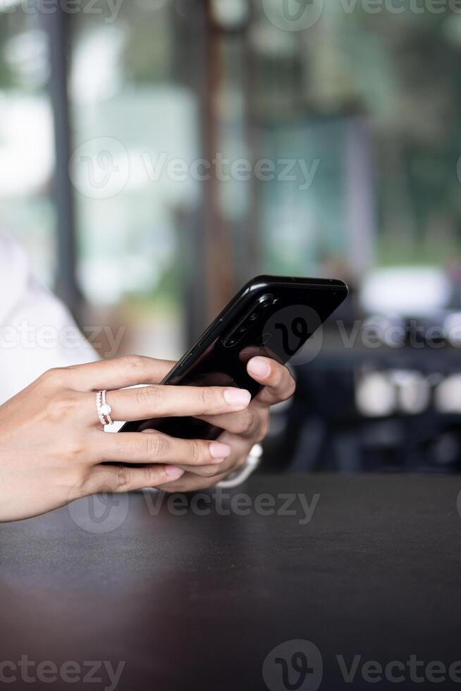 Close up of woman hand using modern smart phone while working in office with computer. and typing a text message on his cell phone. photo