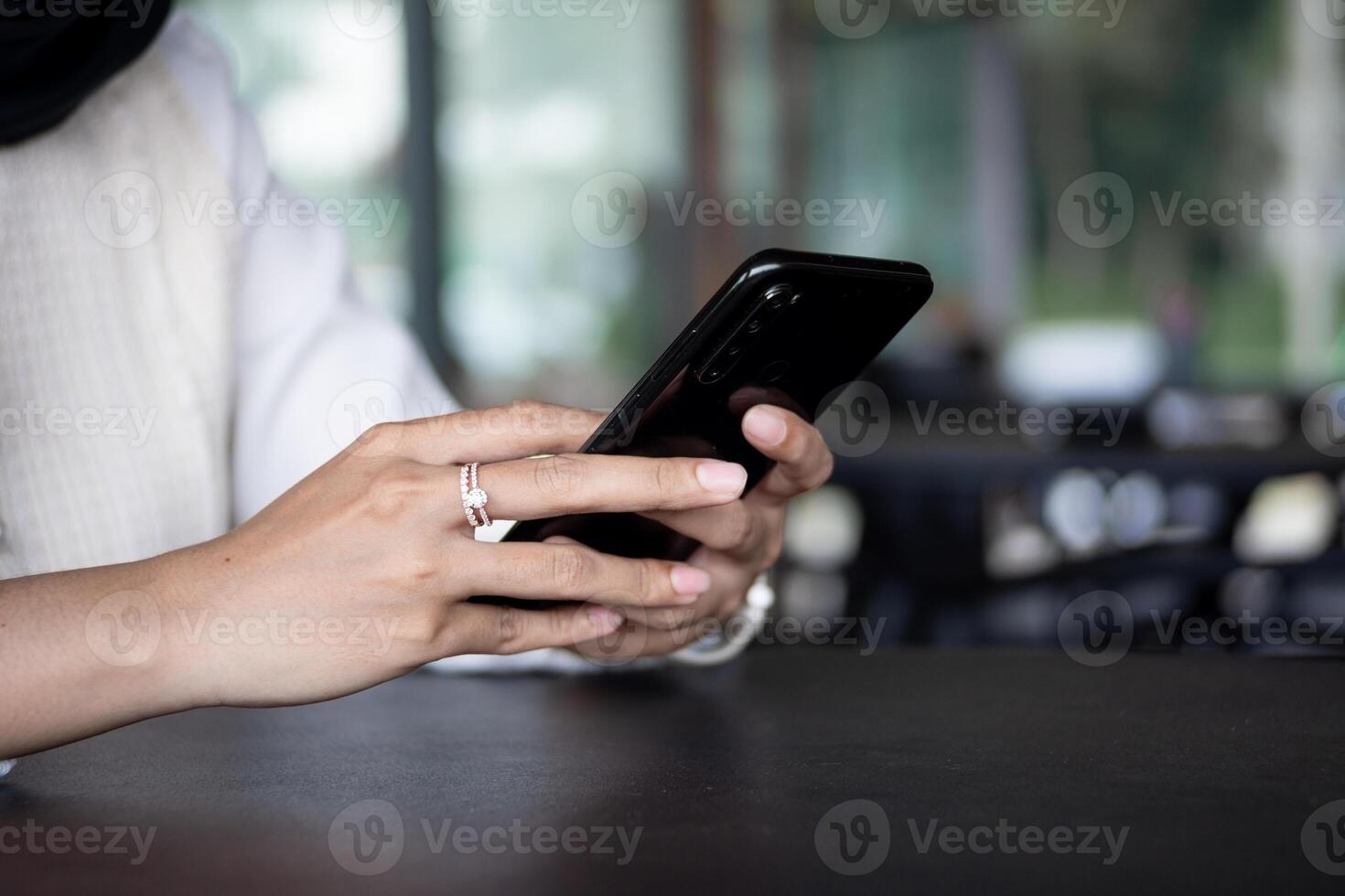 Close up of woman hand using modern smart phone while working in office with computer. and typing a text message on his cell phone. photo