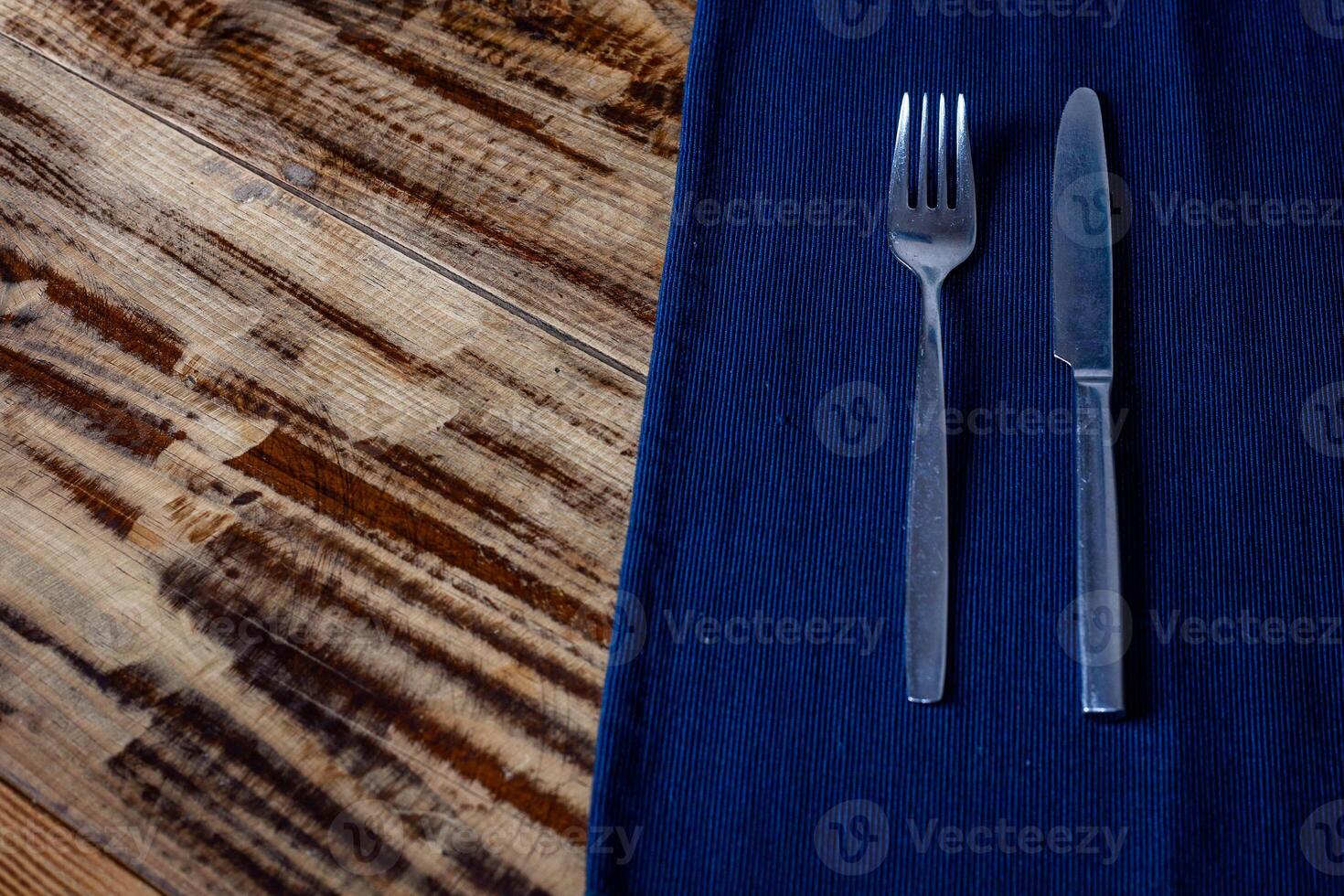 Stylish silver fork and knife resting on a blue cloth, adding elegance to any restaurant table setting. photo