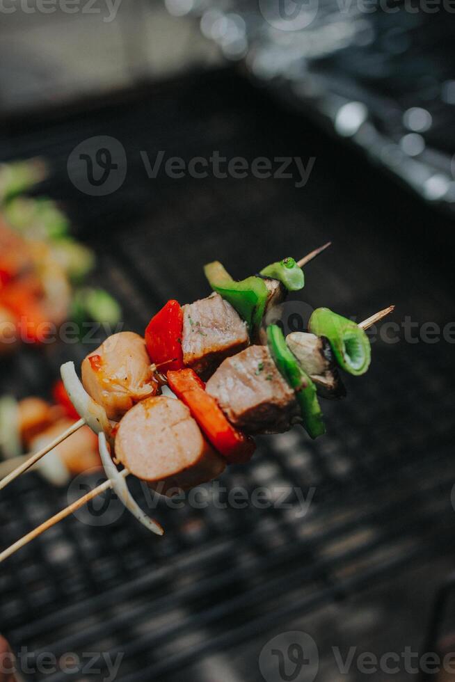 Juicy slices of meat with sauce and vegetables are cooked over an open fire. Snacks are cooked on a metal grill and ready to be served photo