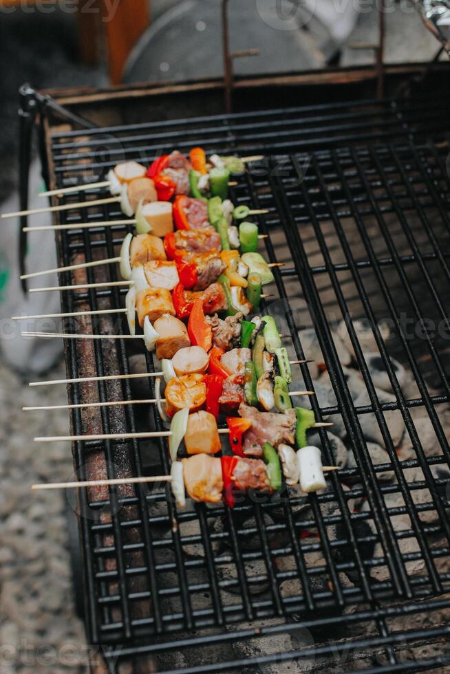 Juicy slices of meat with sauce and vegetables are cooked over an open fire. Snacks are cooked on a metal grill and ready to be served photo