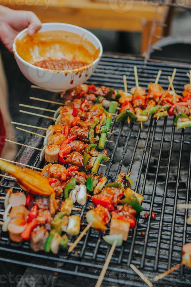 Juicy slices of meat with sauce and vegetables are cooked over an open fire. Snacks are cooked on a metal grill and ready to be served photo