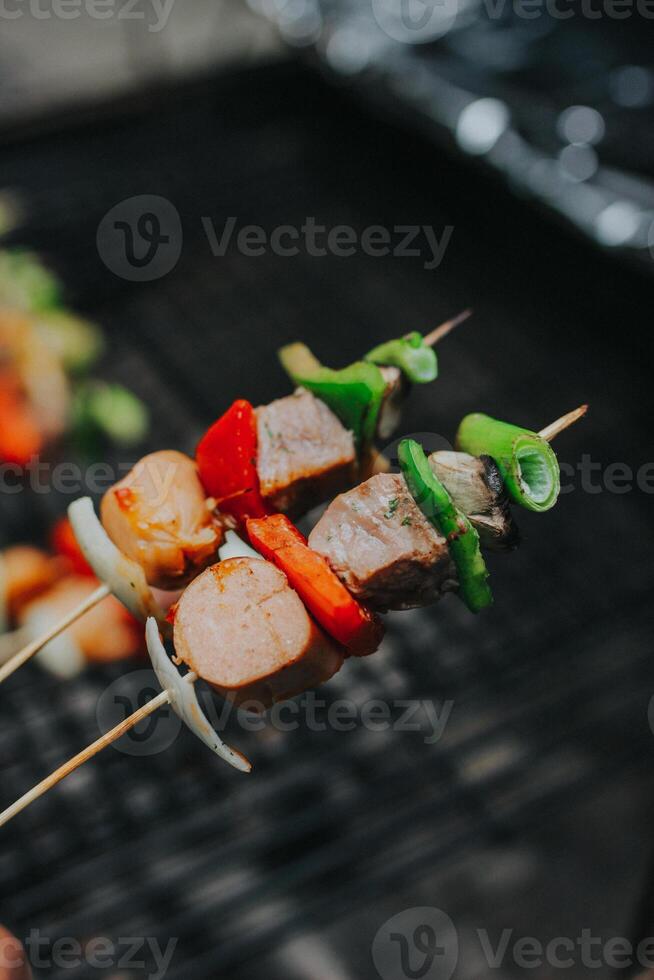 Juicy slices of meat with sauce and vegetables are cooked over an open fire. Snacks are cooked on a metal grill and ready to be served photo