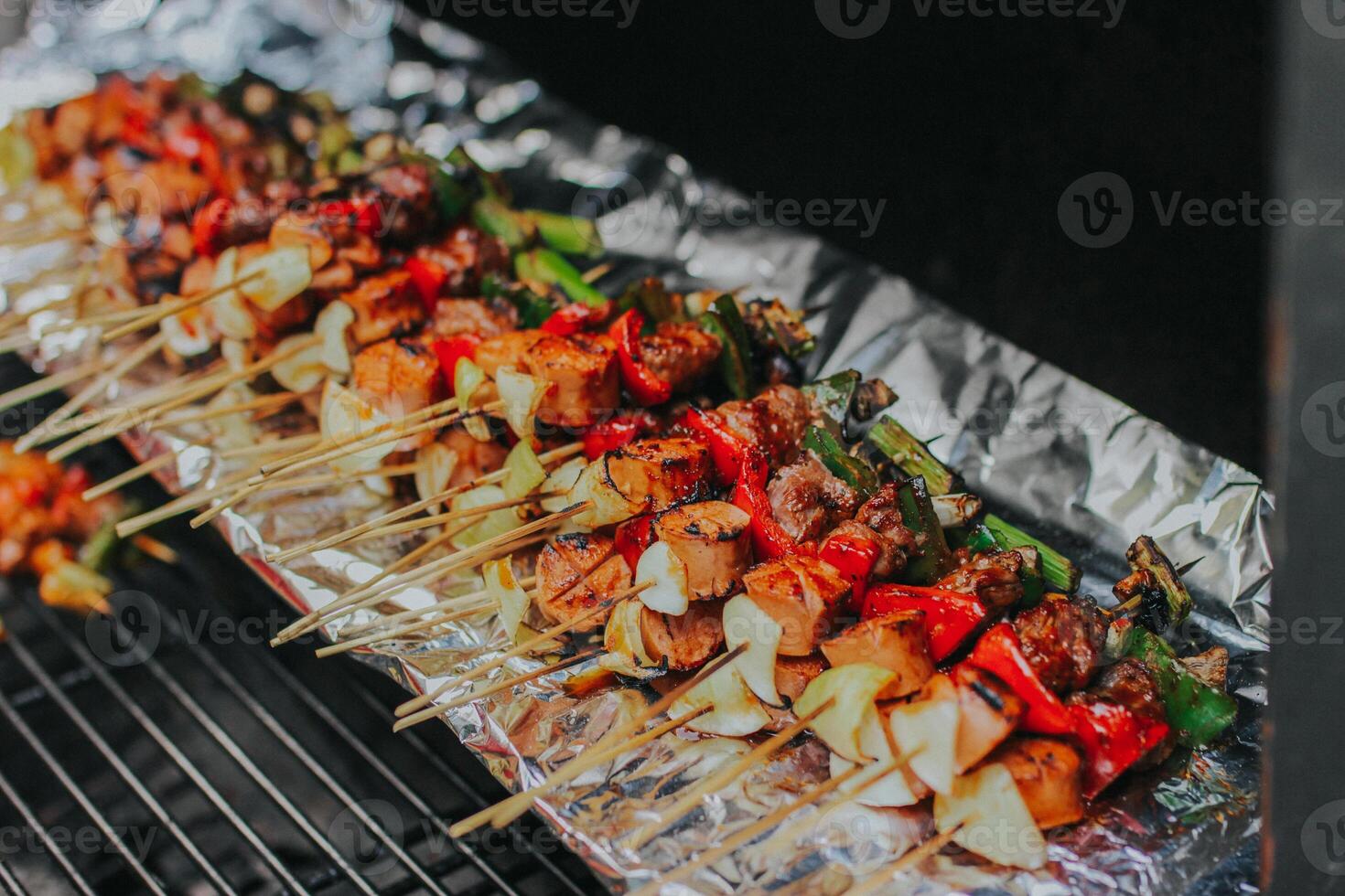 Juicy slices of meat with sauce and vegetables are cooked over an open fire. Snacks are cooked on a metal grill and ready to be served photo