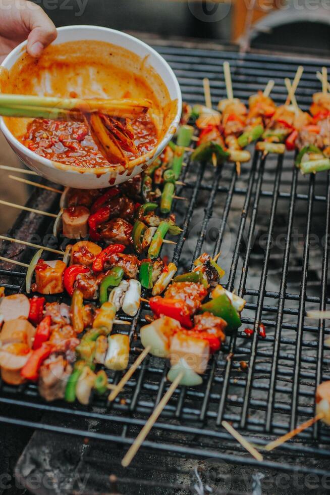 Juicy slices of meat with sauce and vegetables are cooked over an open fire. Snacks are cooked on a metal grill and ready to be served photo