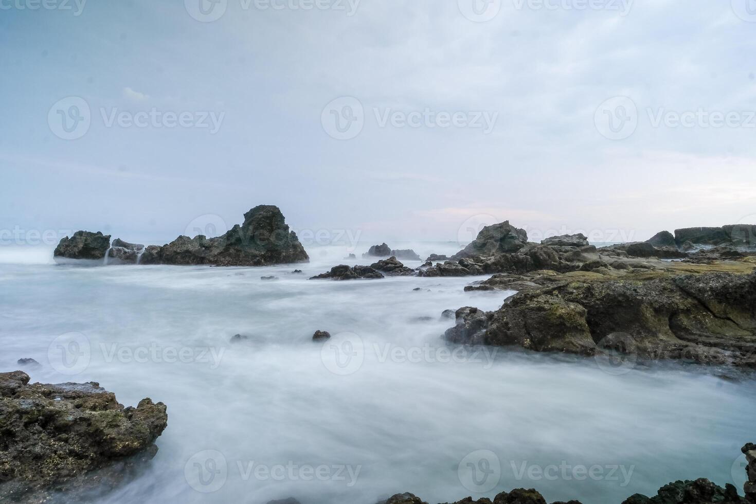 seascape is very beautiful with coral rocks and sea water that looks very soft like cotton at Sawarna Beach, Indonesia. slow shutter speed effect photo