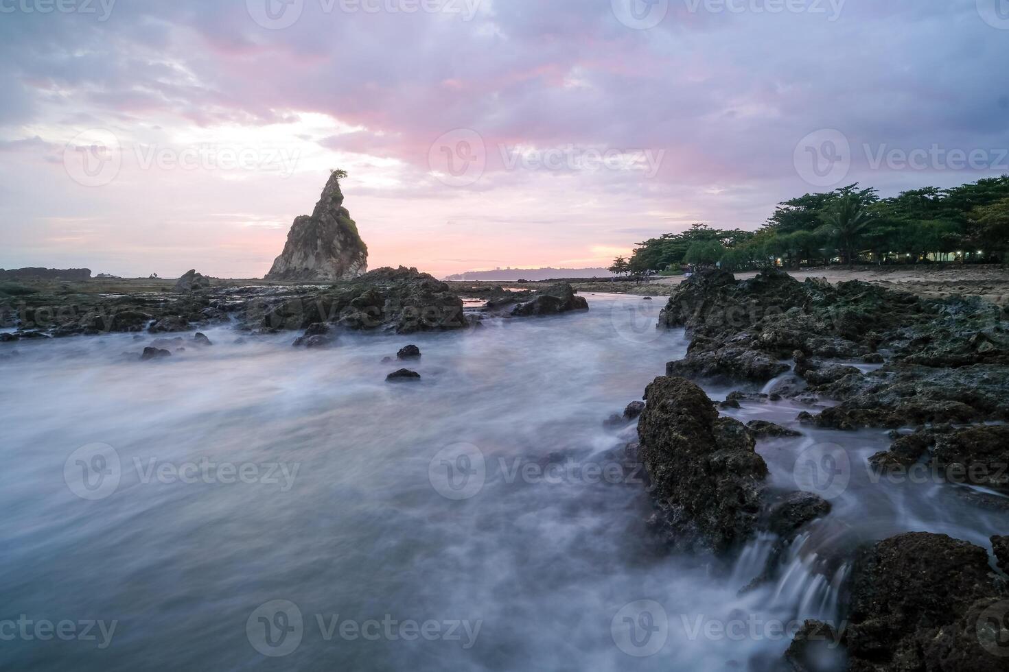 seascape is very beautiful with coral rocks and sea water that looks very soft like cotton at Sawarna Beach, Indonesia. slow shutter speed effect photo
