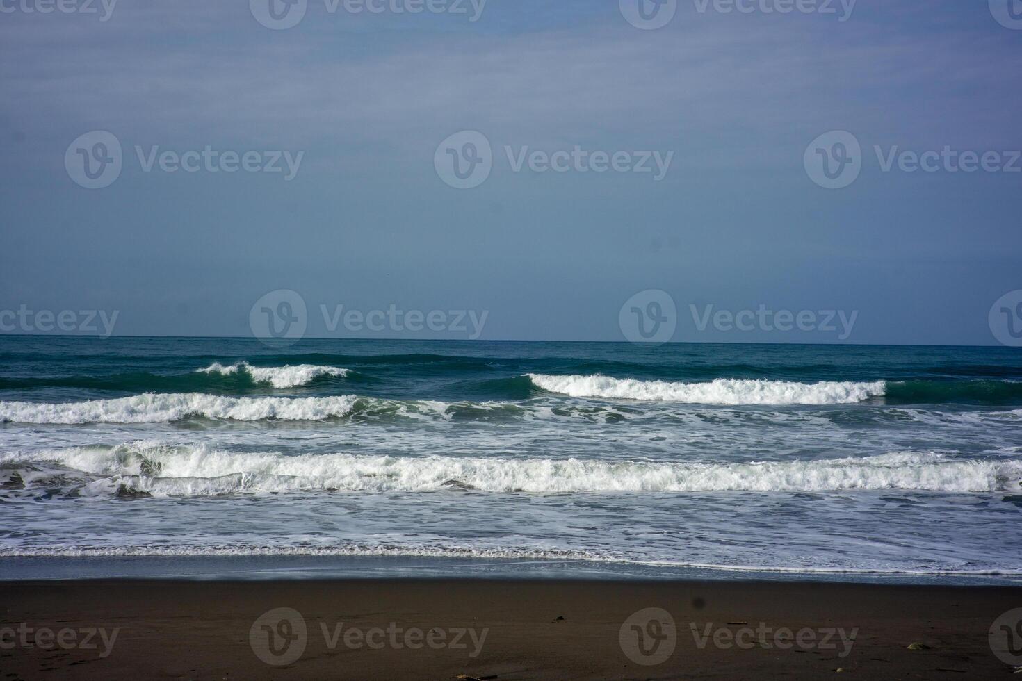 powerful foamy sea waves rolling and splashing over water surface against cloudy blue sky photo