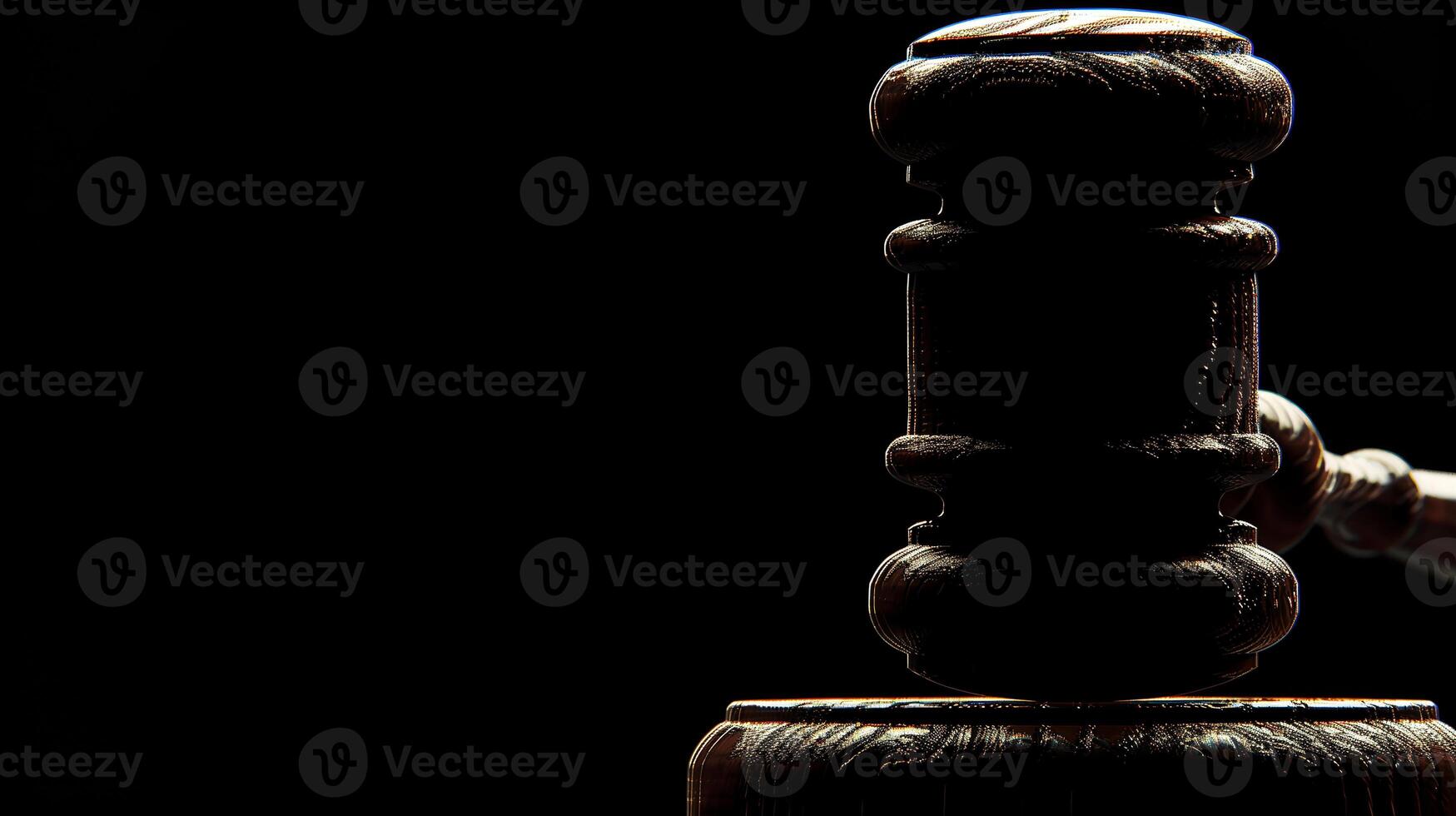 A close-up, dramatic shot of a judge's gavel poised above a sound block, illuminated against a dark background. photo