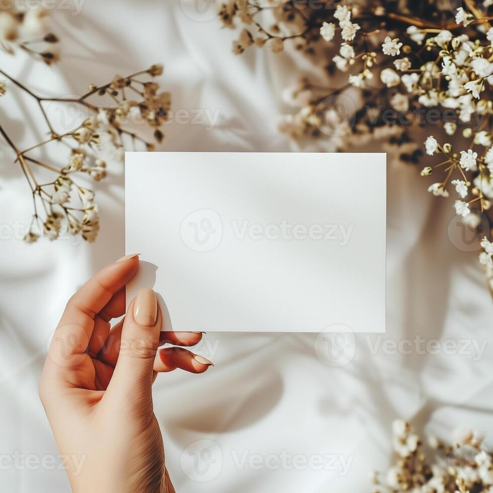 A hand holding a blank note card with a floral background. photo