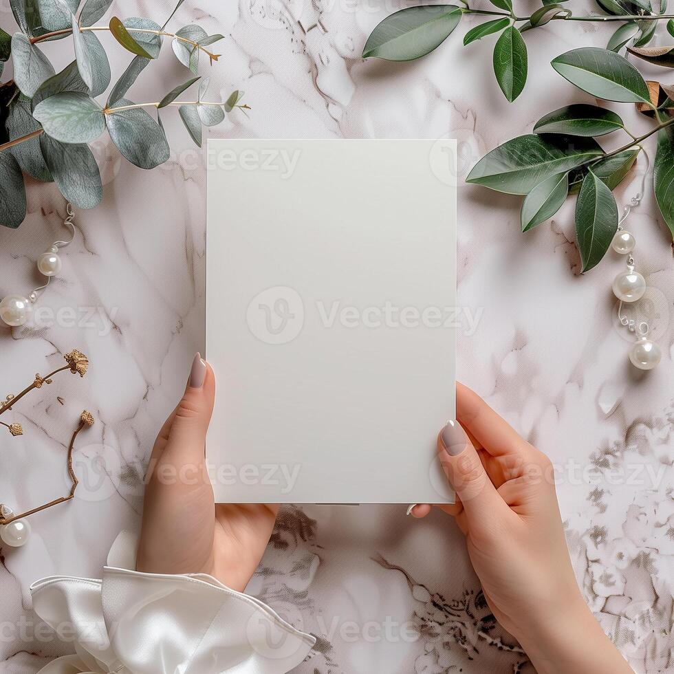 Blank paper in woman's hands. There are some leaves and pearls on the marble table. photo