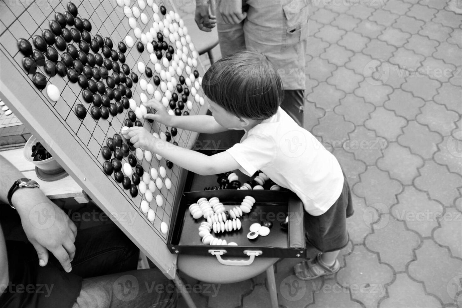 Boy playing chinese game Go, close up, black and white photo