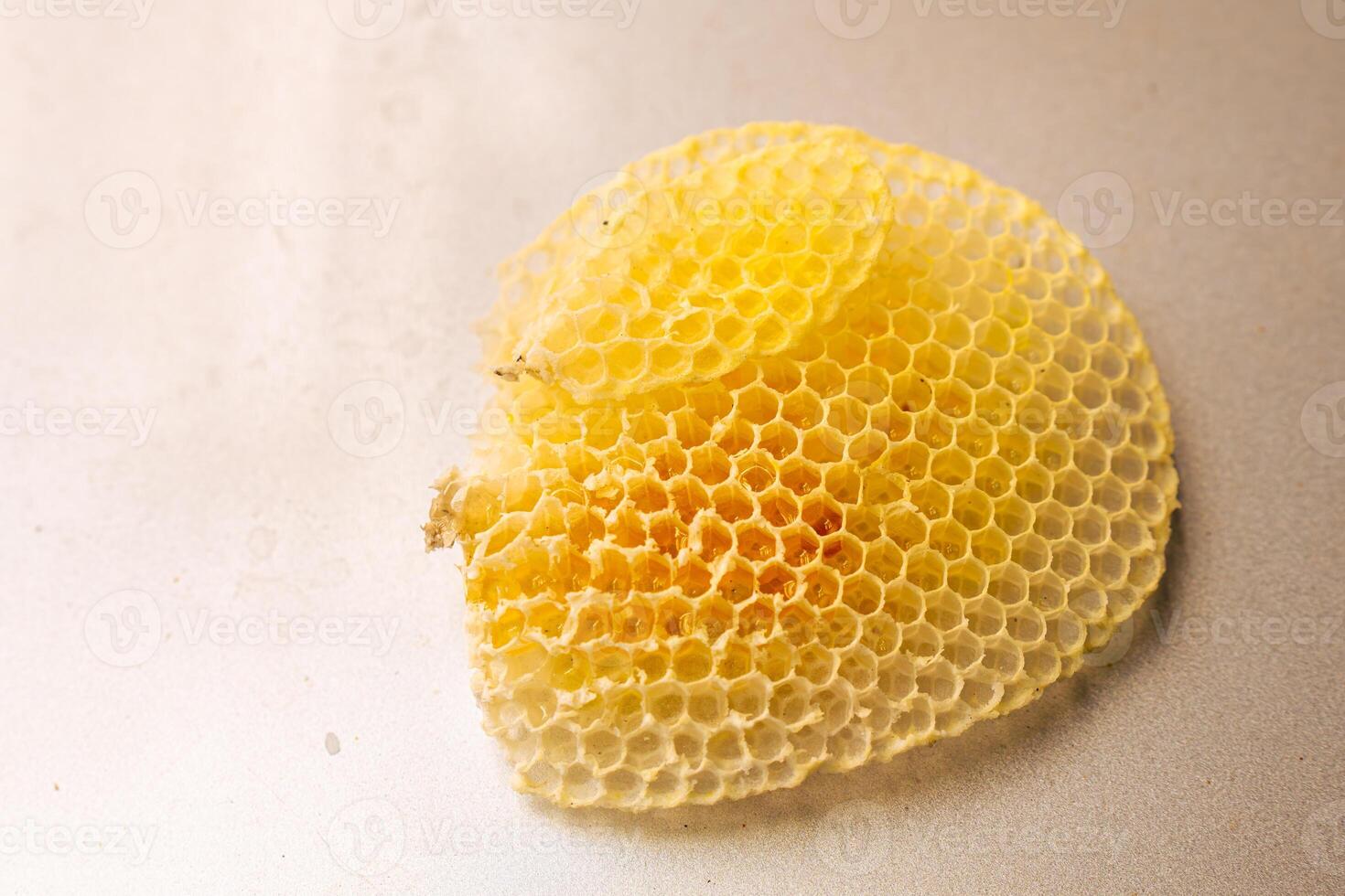 A yellow honeycomb filled with honey on a wall background. photo