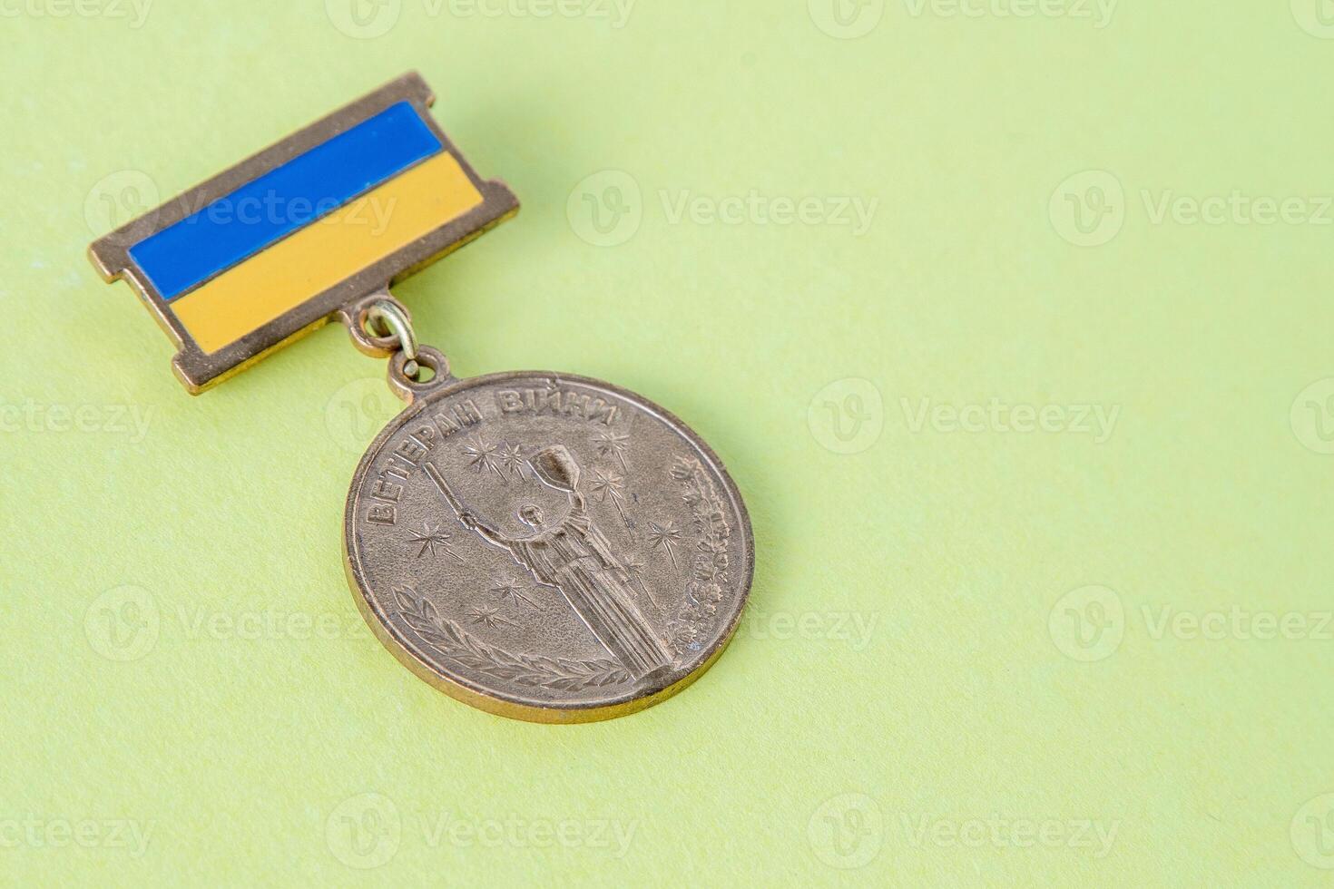 Military medal with the Ukrainian flag. The inscription in Ukrainian is War Veteran . Motherland holds a shield and sword. Ukraine, Kyiv - February 24, 2022. photo