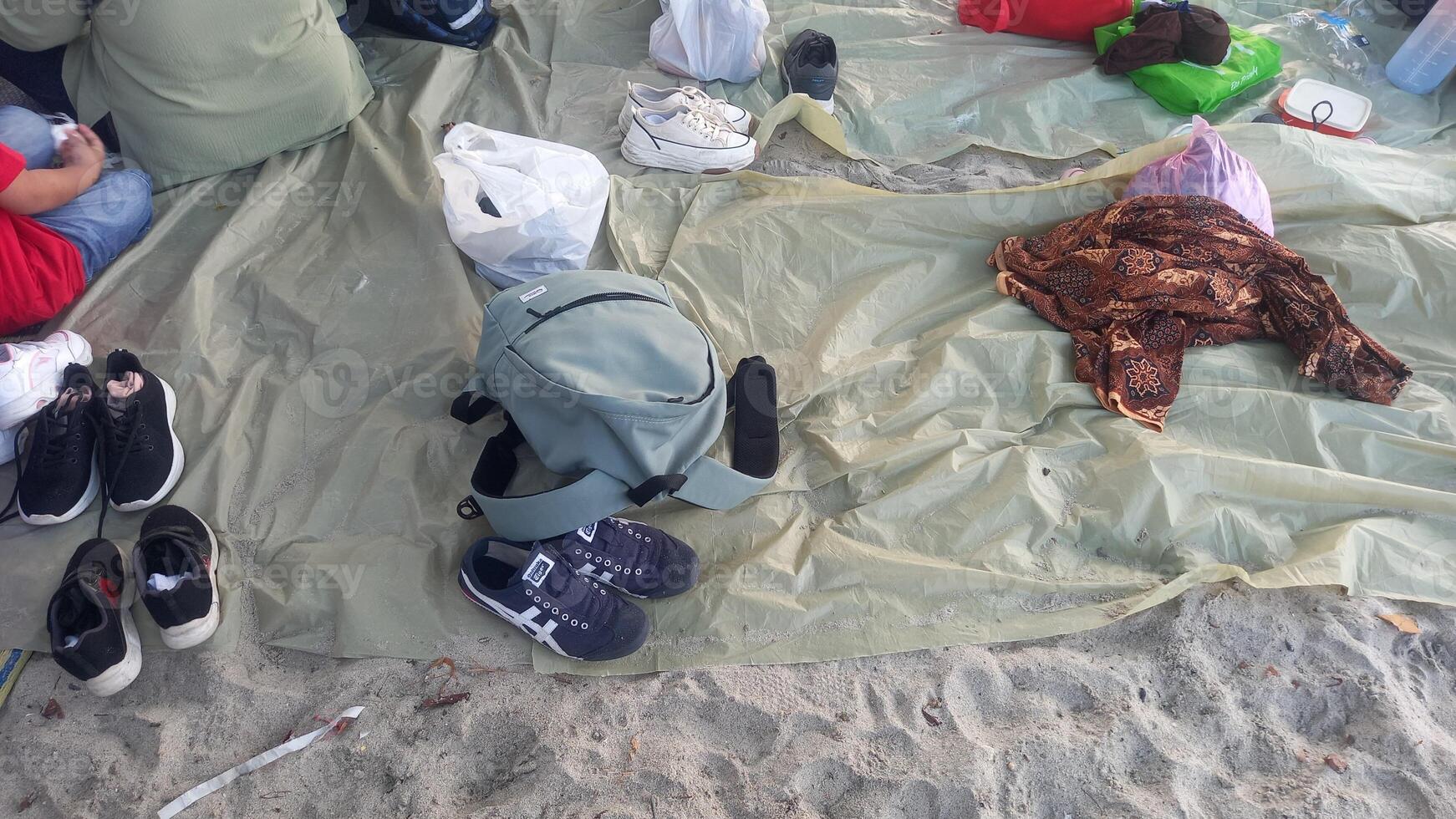 people sitting on the sand with bags and shoes photo