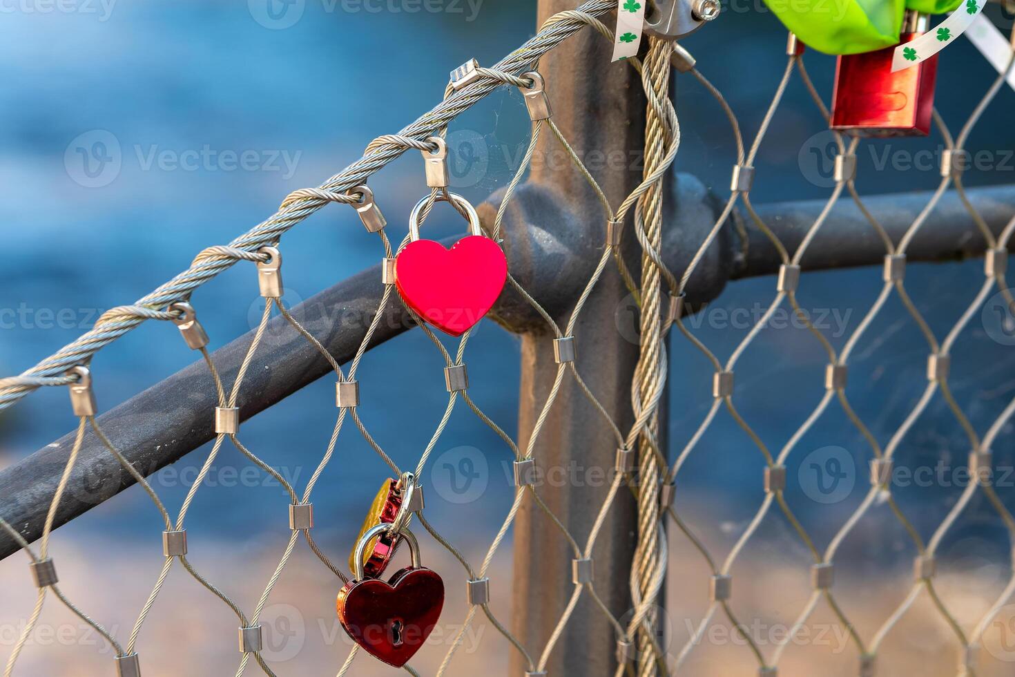 chain link fence with red heart shaped charms hanging from it photo