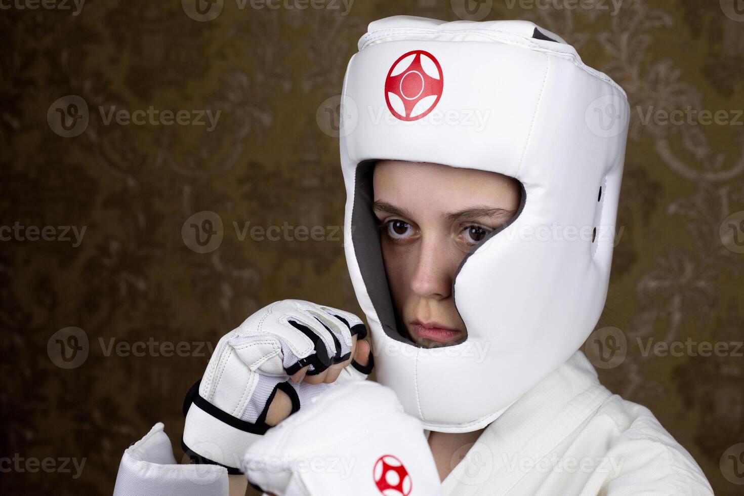 Portrait of girl in protective Kyokushin karate helmet and gloves in protective stance. Girl opponent in martial arts photo