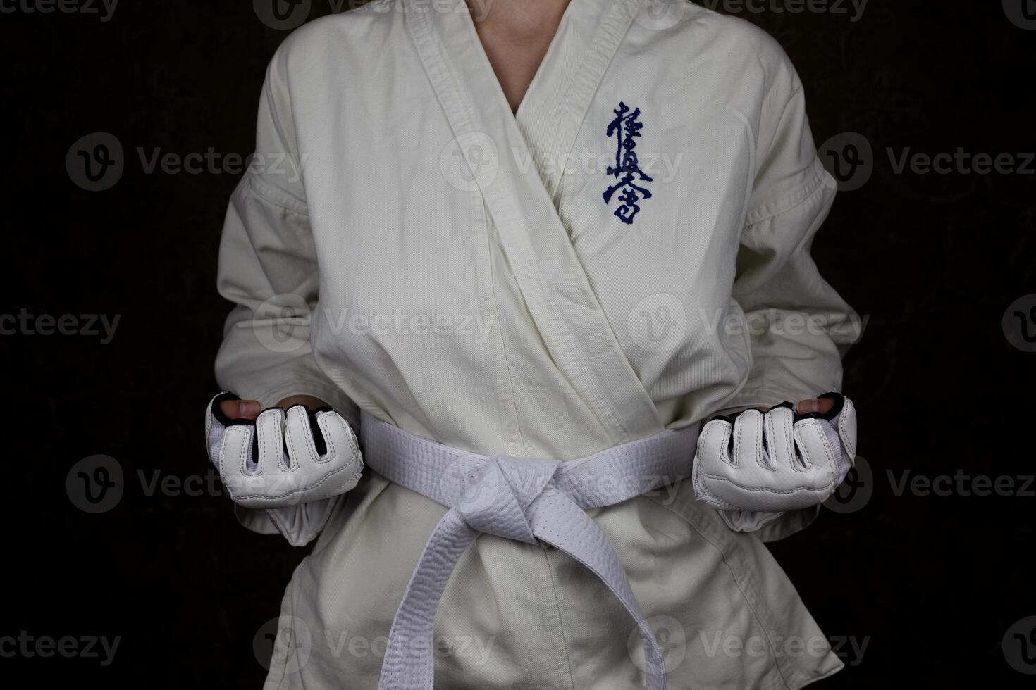 Girl athlete in kimono Kyokushin karate stands in stance with clenched fists photo