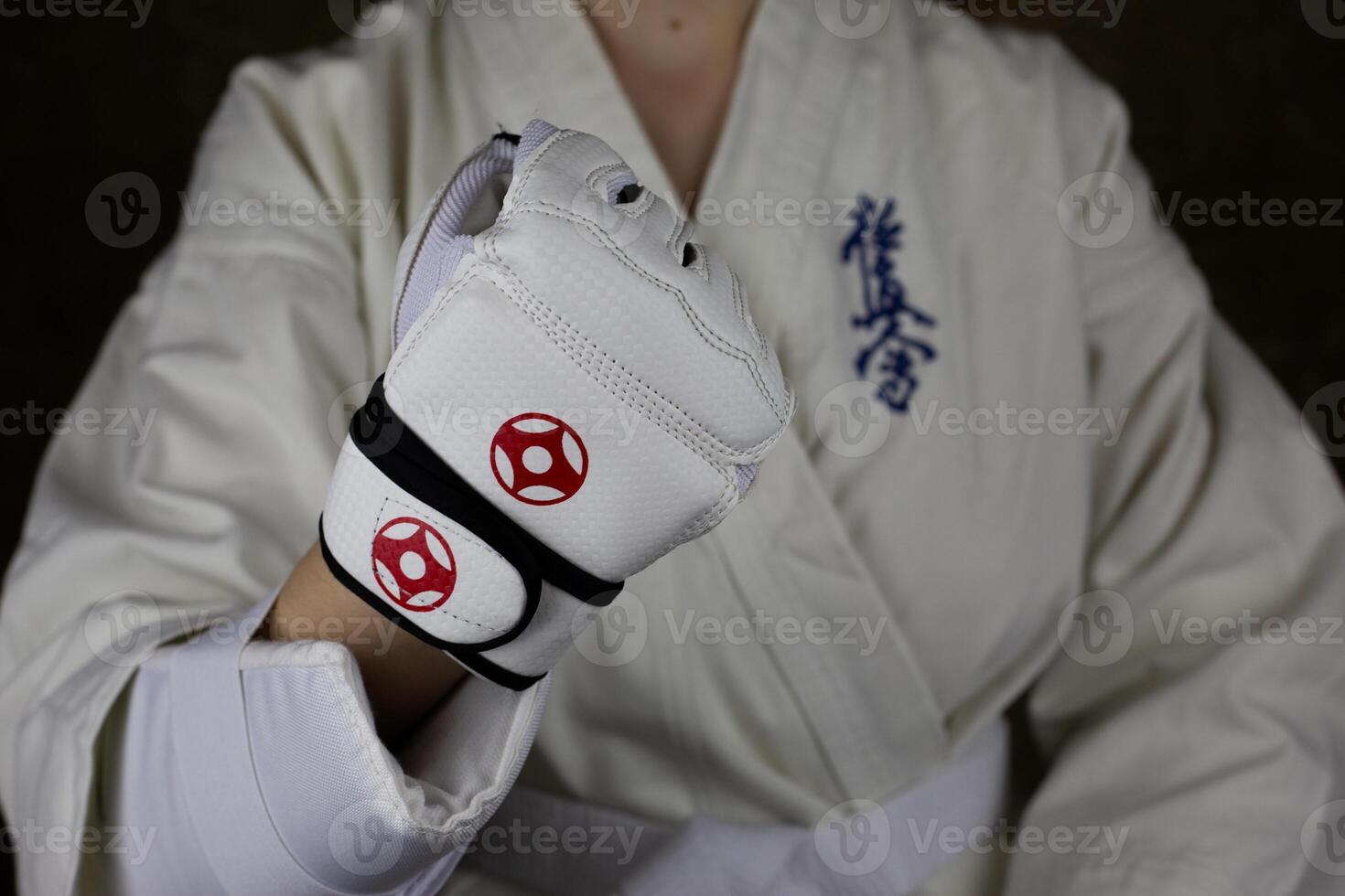 Girl athlete in Kyokushinkai karate demonstrates clenched fist in special protective glove for martial arts photo