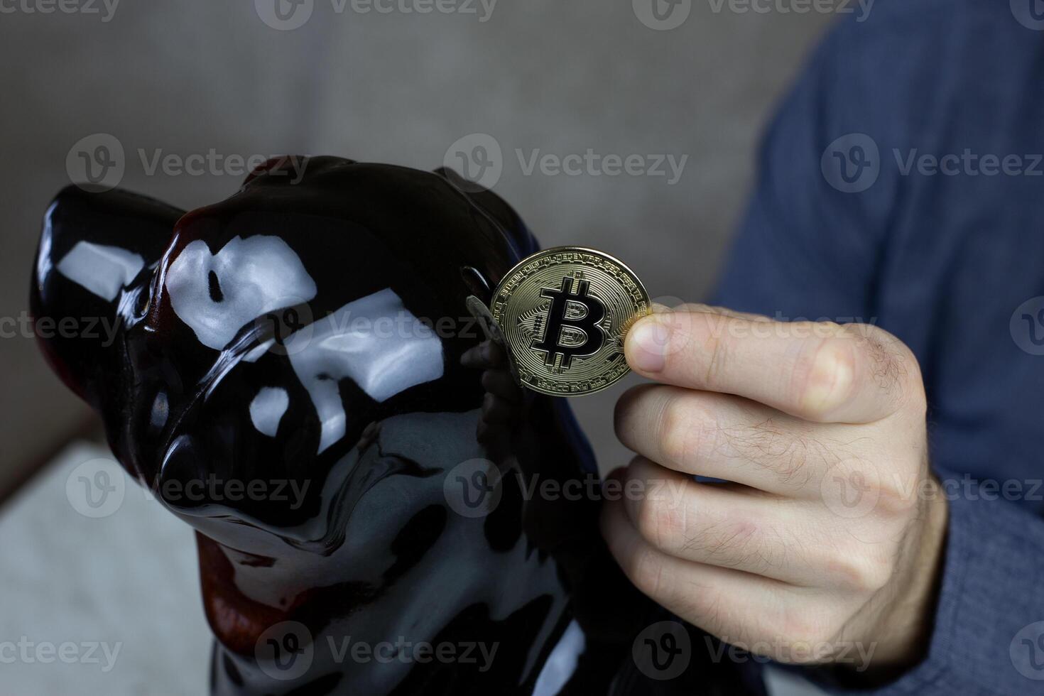 Man hand puts physical version of golden bitcoin into piggy bank, savings in cryptocurrency and investments in the future photo