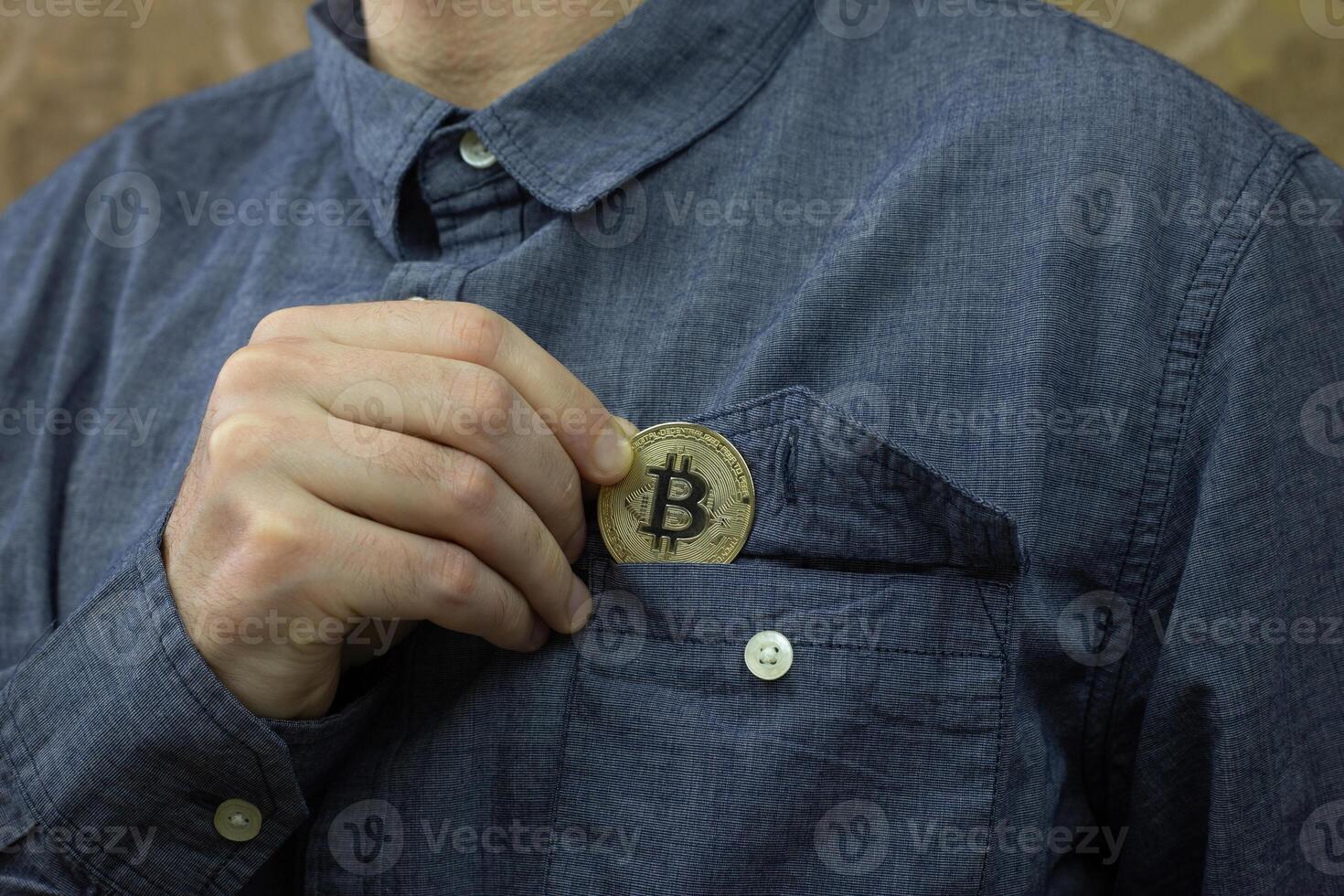 Man puts physical version of Bitcoin in his shirt breast pocket, saving money in cryptocurrency concept, savings and investment photo