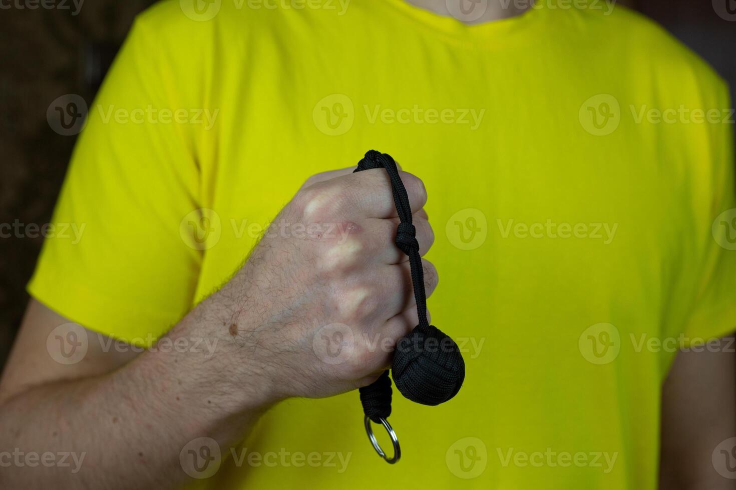 Self-defense keychain made of braided laces with monkey knot with metal ball, baton for self-defense against a criminal on man hand photo