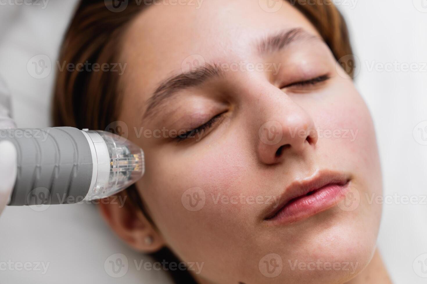 A woman is getting a facial treatment with a machine on her face photo