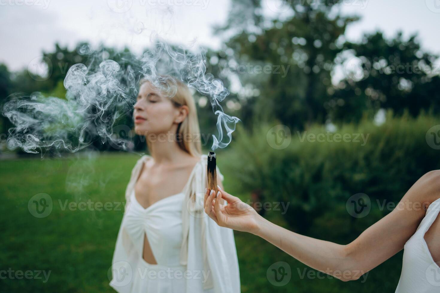 A young woman practices meditation in nature. Meditation with smoke. photo