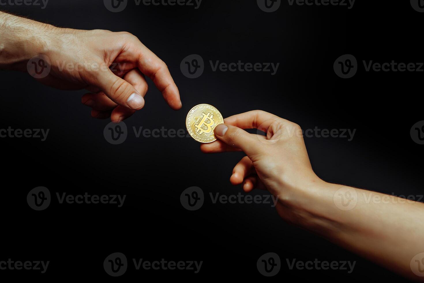 Bitcoin in hand on a dark background. The hand reaches for the cryptocurrency. photo