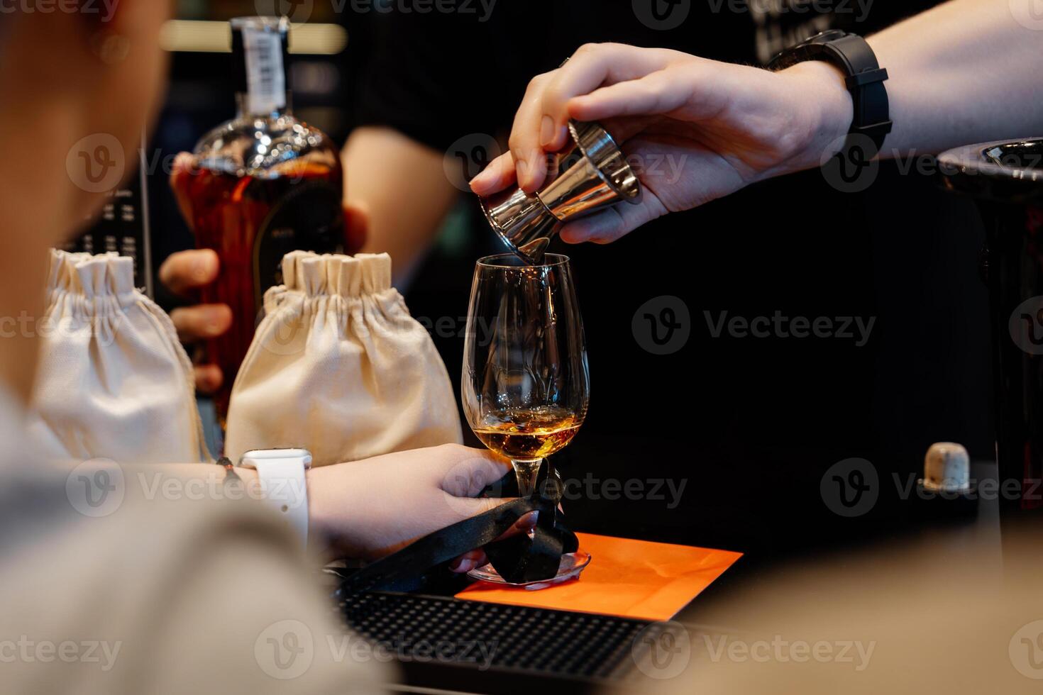 The bartender pours whiskey into a tasting glass for a sample. photo