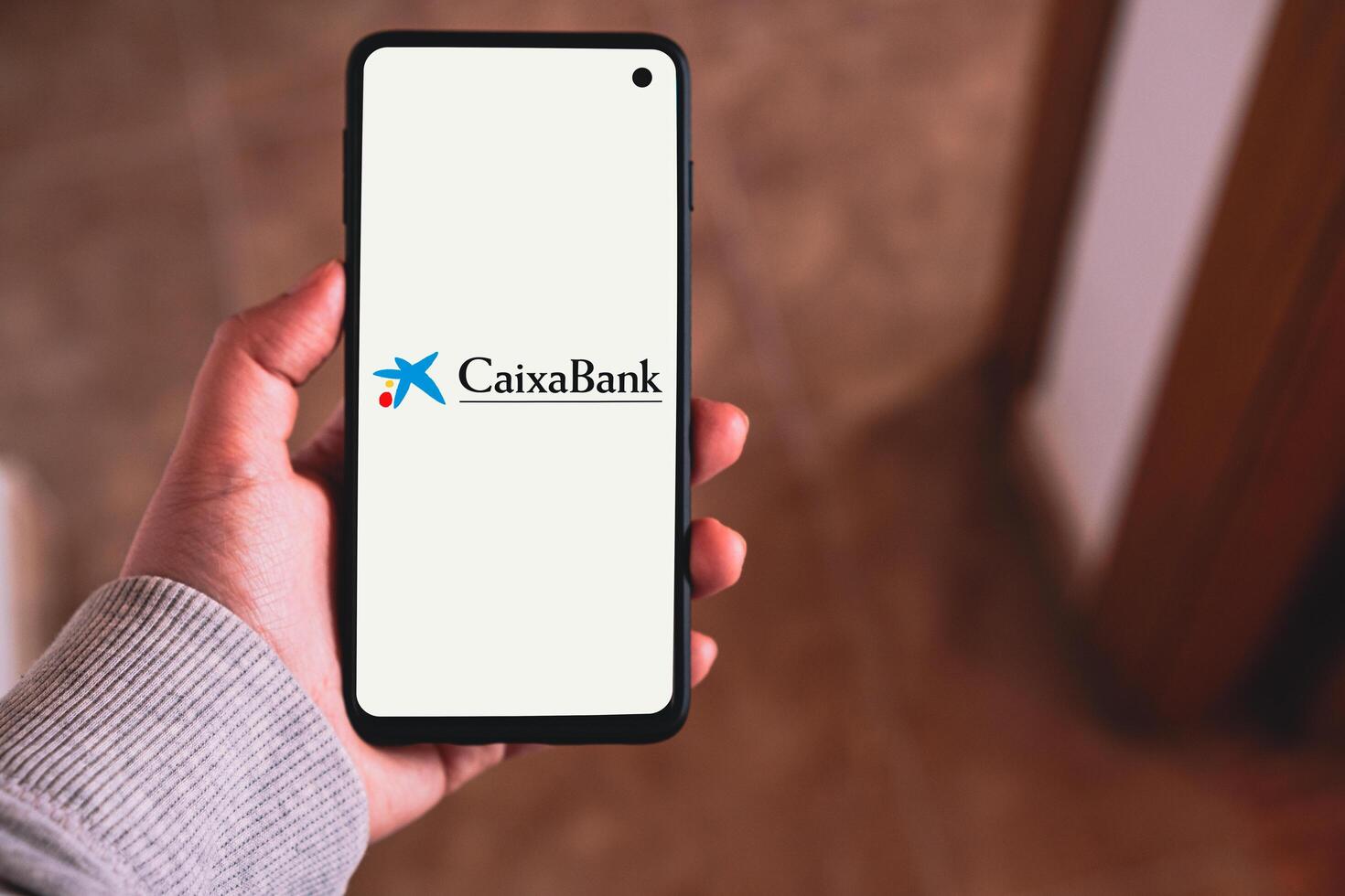 MALAGA - SPAIN - MAY 14 - 2024 - Smartphone with Caixabank bank logo on screen. Spanish banking group. photo