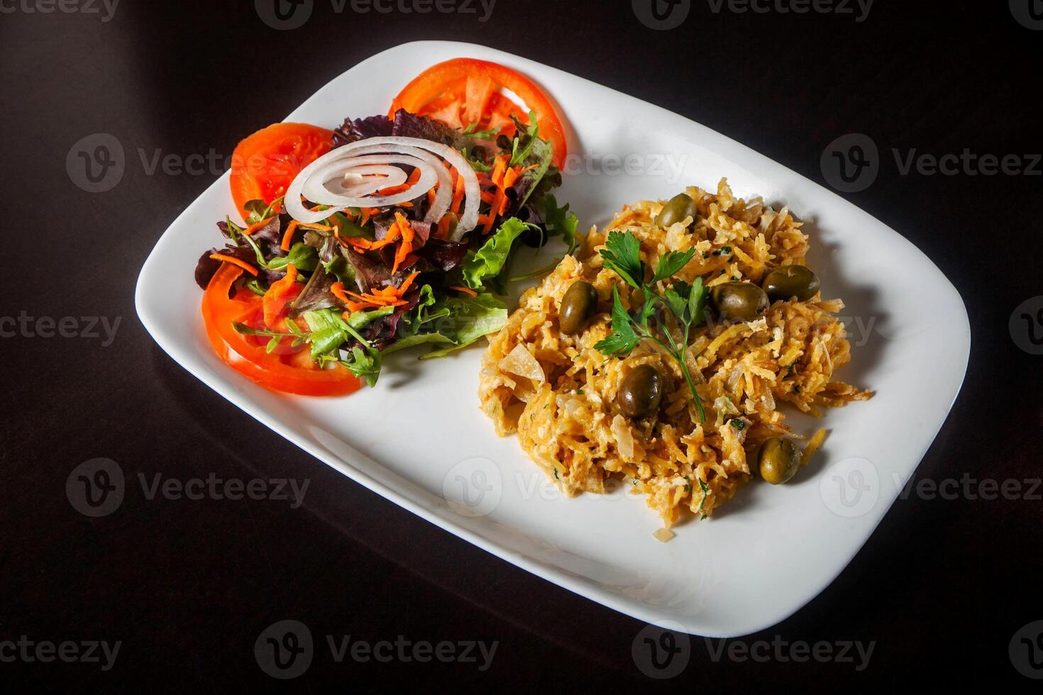 Traditional Portuguese dish, Bacalhau a Bras, with flaked cod, scrambled eggs, potatoes, and olives, garnished with parsley. Iconic flavors captured in a savory plate. photo