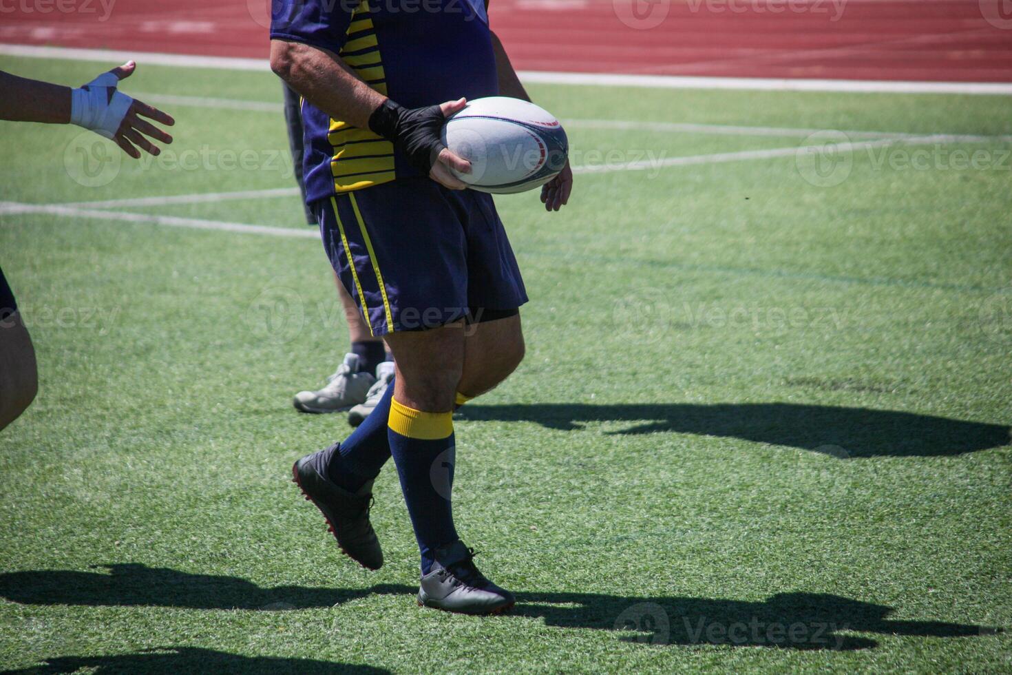 Group of men playing rugby on grass field, tackling and passing ball in action-packed match. photo