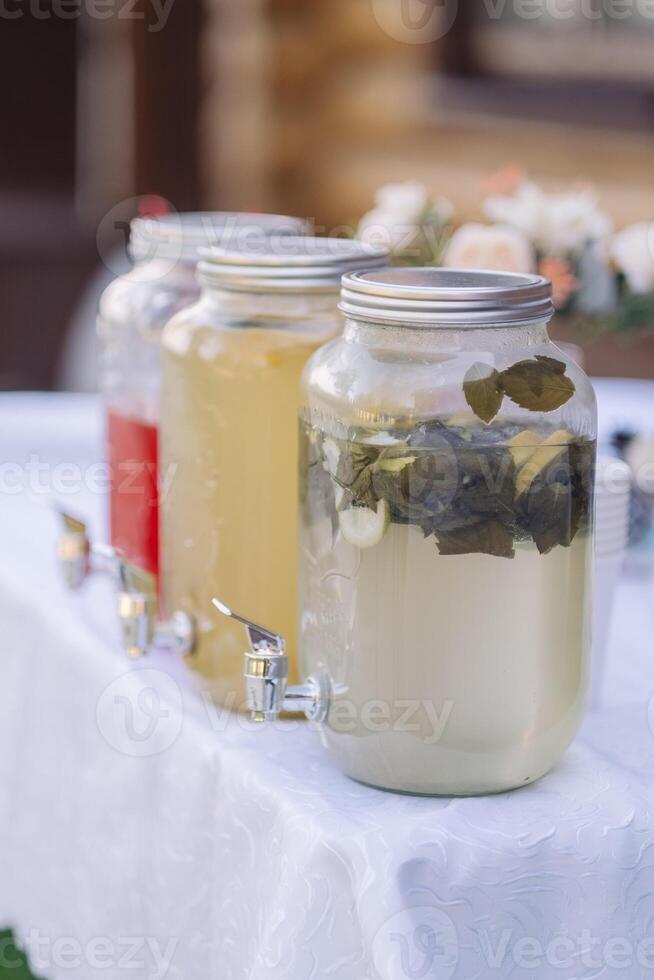 water from jug pouring into glass on wooden table outdoors photo