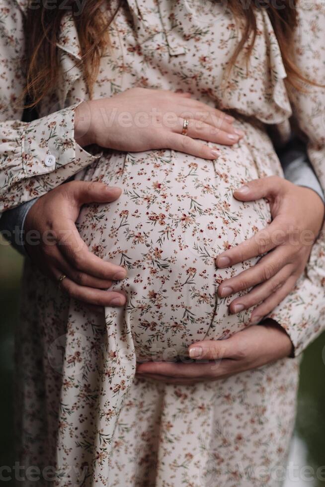 A guy and a pregnant girl hug and make a heart on her tummy with their own hands. Valentine's day, holiday concept - family, couple, man and woman, love, pregnancy. Black and white photo, monochrome. photo
