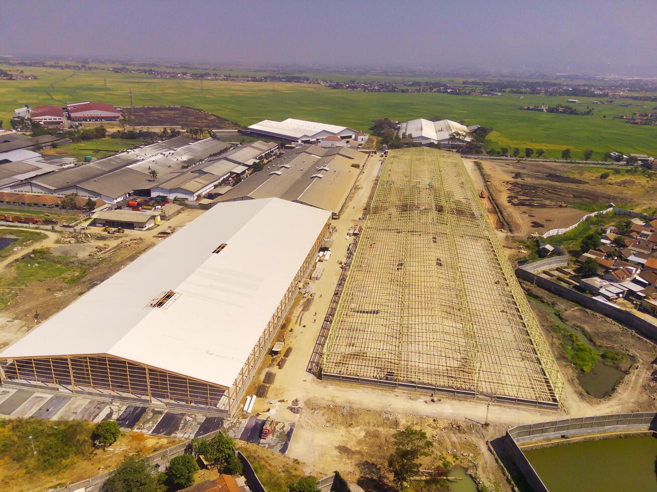 Factory under construction. Aerial drone photo of a factory being built by workers on the edge of Bandung City. Top view of Factory construction