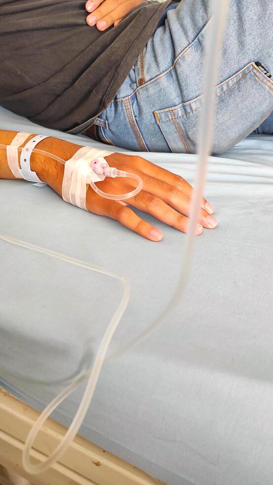 Health and Medical Photography. Photo A patient lies in bed, with his arm infused with nutrients. Functions to maintain electrolyte balance, hydrate the body, restore pH and as a fluid resuscitator.