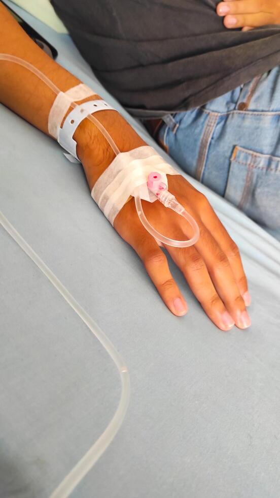 Health and Medical Photography. Photo A patient lies in bed, with his arm infused with nutrients. Functions to maintain electrolyte balance, hydrate the body, restore pH and as a fluid resuscitator.