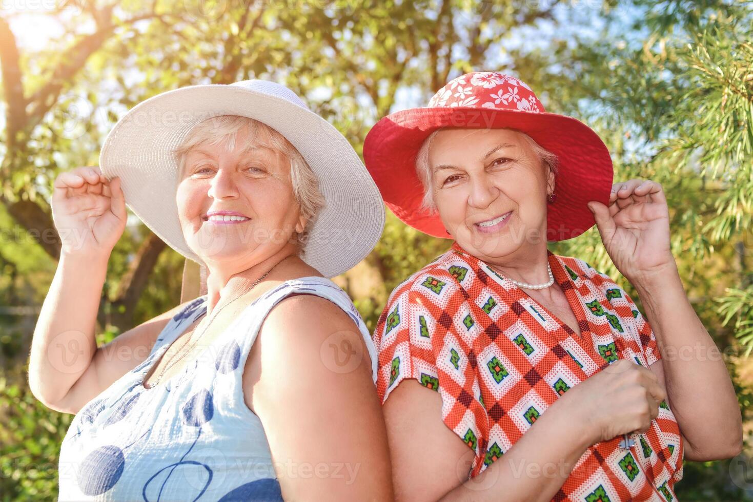 Walk in the garden. Two retired women best friends in hats walk happily in the garden. photo
