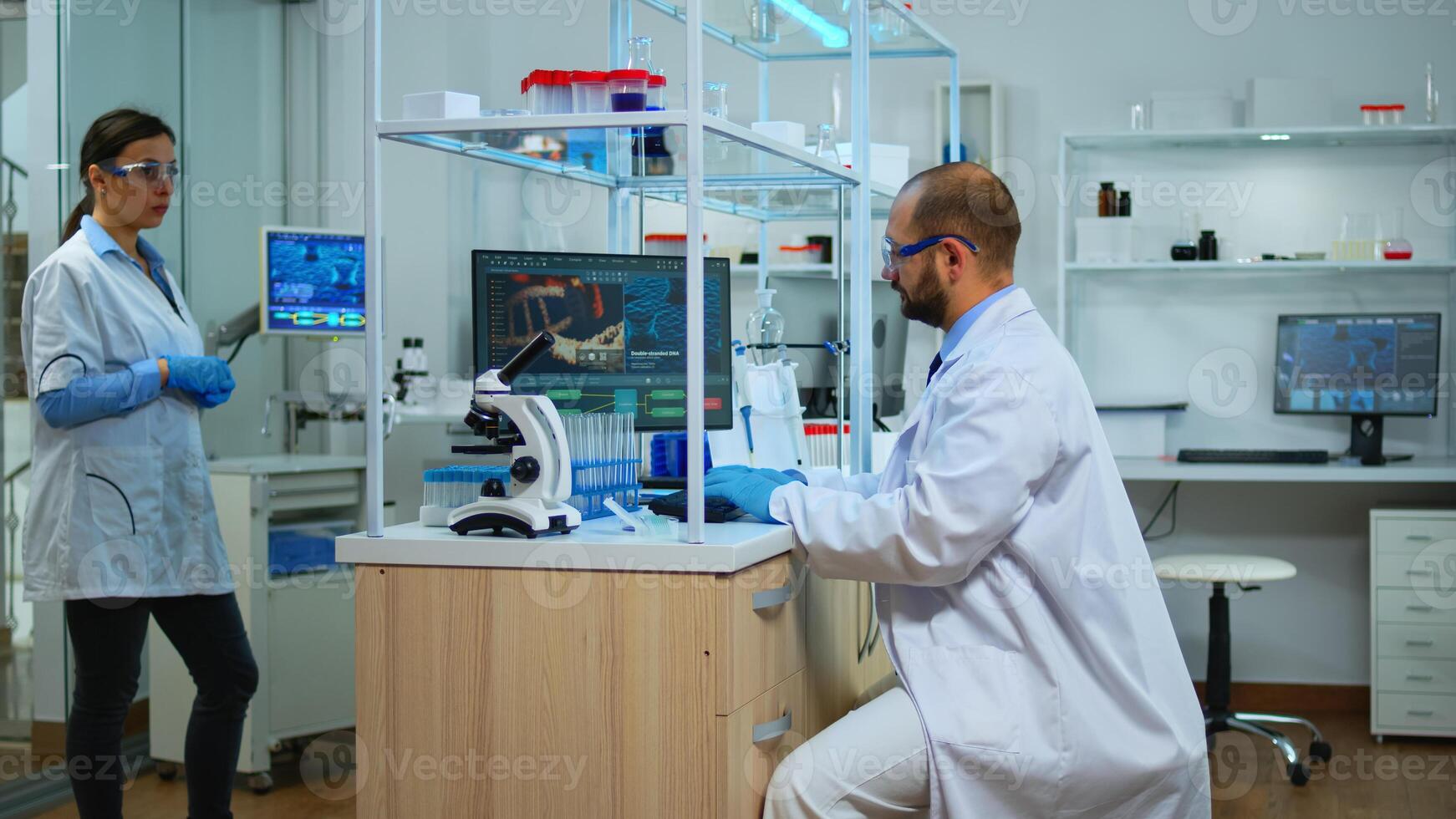Scientist working in modern equipped laboratory cheching virus development with microscope. Multiethnic team examining vaccine evolution using high tech and chemistry tools for scientific research. photo
