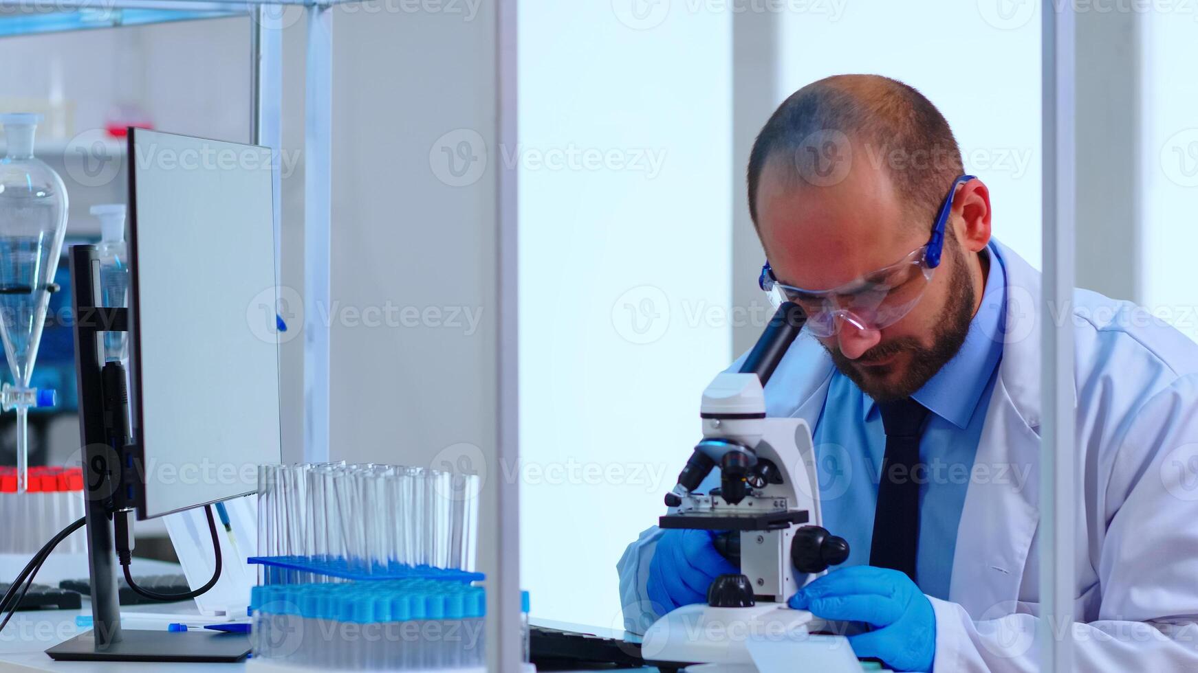 Medical research scientist conducting vaccine development under digital microscope in a biological applied science laboratory. Caucasian lab engineer in white coat working on medical treatment photo