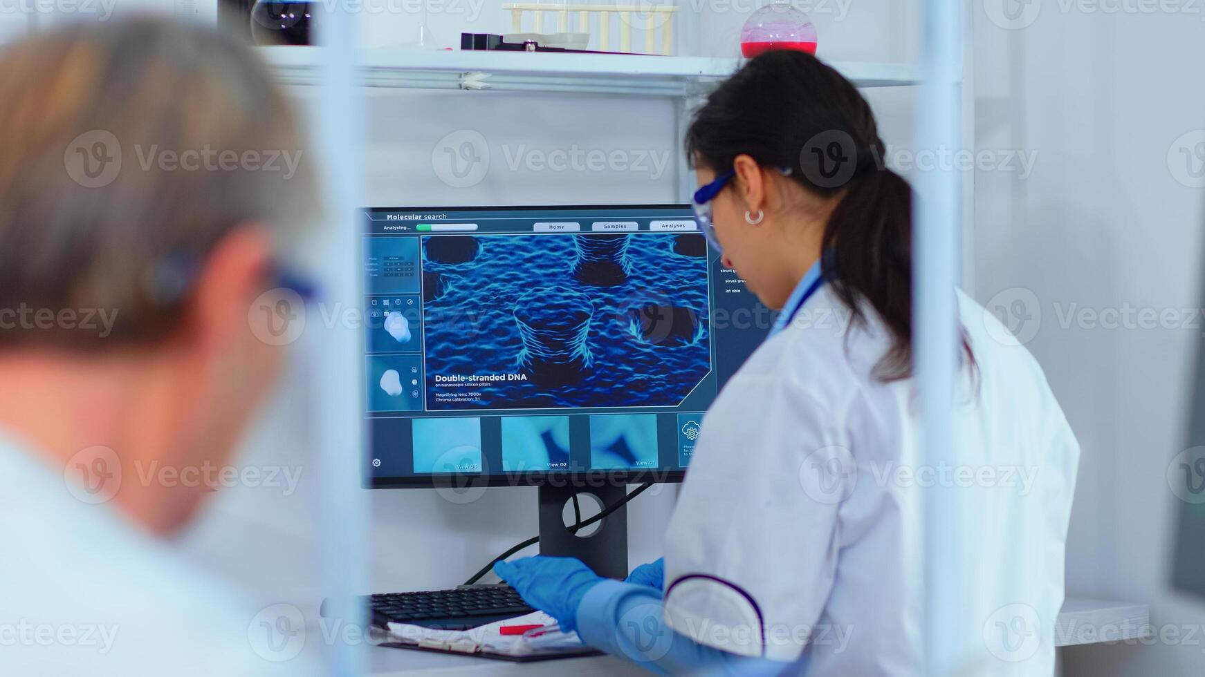 Scientist nurse typing on computer in scientific modern equipped laboratory. Multiethnic stuff examining vaccine evolution using high tech and technology researching treatment against covid19 virus photo
