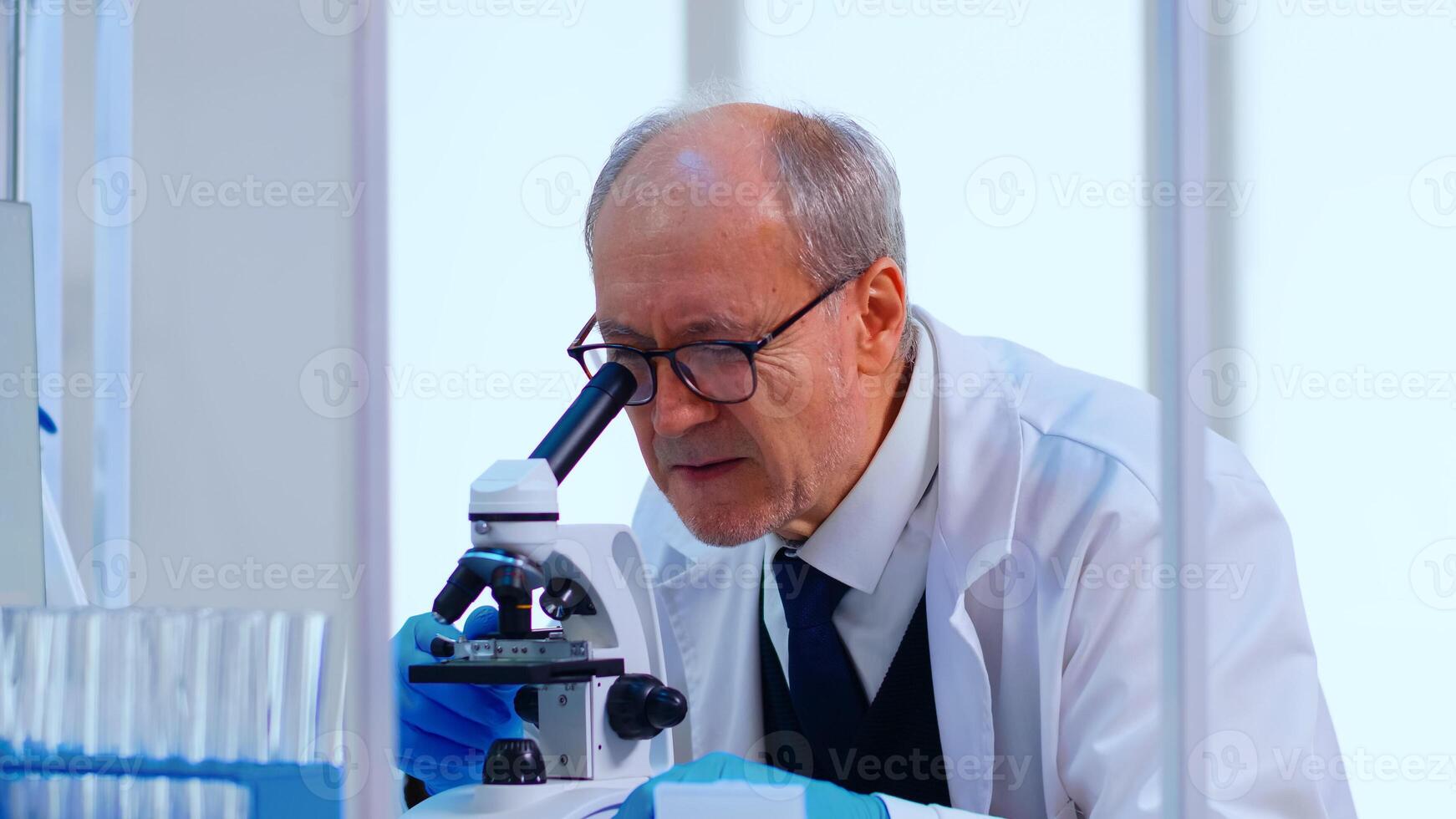 Senior lab technician examining samples and liquid using microscope in equipped laboratory. Scientist working with various bacteria, tissue and blood samples, pharmaceutical research for antibiotics photo