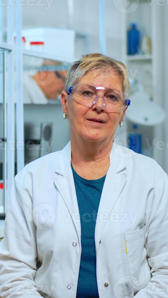 Portrait of senior scientist woman looking at camera in modern equipped lab. Multiethnic team examining virus evolution using high tech and chemistry tools for scientific research, vaccine development photo
